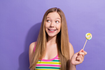 Photo of funny cute schoolgirl with straight hairdo dressed striped top look empty space hold lollipop isolated on violet background