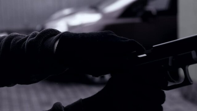 Black and white video hands of a man in gloves with a weapon or pistol reloading him. Bandit, criminal, thief, robber