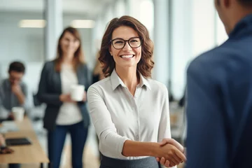 Fotobehang Happy mid aged business woman manager handshaking at office meeting. Smiling female hr hiring recruit at job interview, bank or insurance agent, lawyer making contract deal with client at work. © GustavsMD