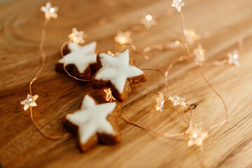 Gingerbread cookies in the shape of stars on a wooden brown natural table against a background of bokeh of New Year's golden lights. Christmas background. Winter card. Delicious pastries close-up