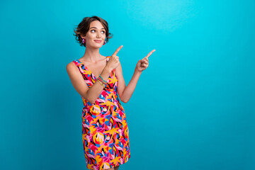 Portrait of positive person with short hairstyle wear colorful dress indicating look at sale empty space isolated on blue color background