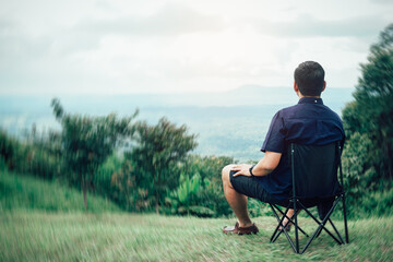 Traveling man relaxing after hiking Sit on a chair and admire the mountain views and natural beauty