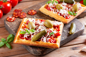 Waffle pizza with tomato sauce, olive, cucumber, sausages and cheese. Trend of the year