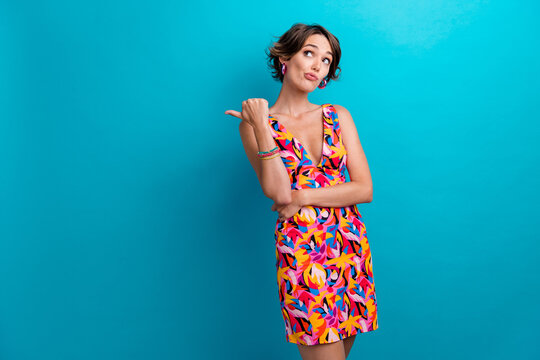 Portrait of minded confused funny person wear colorful dress indicating look at offer empty space isolated on blue color background
