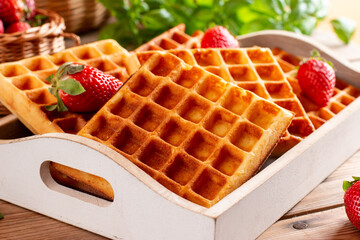 Square belgian waffles with strawberry on a table. Tasty sweet sugary waffles