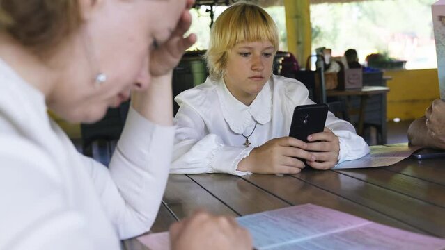 A girl is sitting in a restaurant, studying the menu on a smartphone on the website. Close-up.
