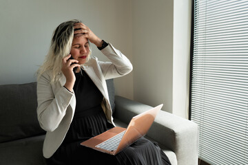 Elegant woman working online with her laptop and smartphone from home.