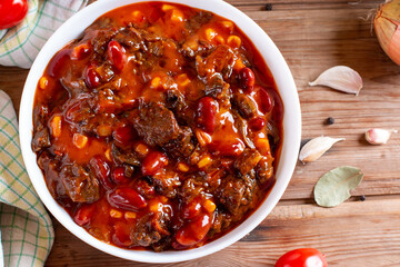 Goulash, beef stew or mexican dish chili con carne soup with meat, vegetables and spices on table. Rustic style. Top view.