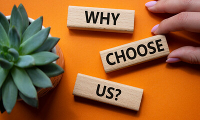 Why choose us symbol. Concept words Why choose us on wooden blocks. Beautiful orange background...