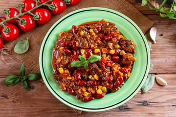 Hot and spicy fresh made mexican dish chili con carne soup with meat, vegetables and red beans on table. Goulash