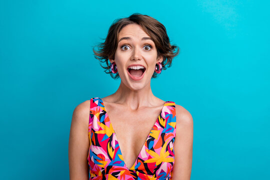 Portrait of astonished overjoyed person with short hairstyle wear colorful dress staring open mouth isolated on blue color background