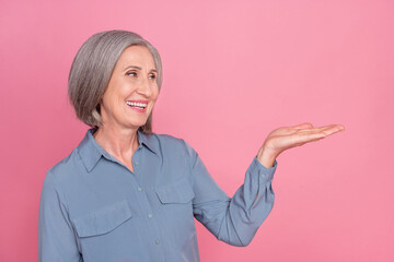 Photo of good mood pensioner woman with bob hairstyle dressed blue stylish shirt palm presenting...