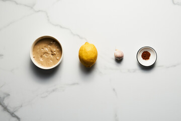Tarator - Lebanese sauce from tahini with garlic, lemon juice and water. White or cream colored sauce in a jar on a marble background