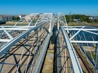 New triple tied-arc railroad bridge with four tracks, walkway and bicycle lane over Vistula river in Krakow, Poland. Aerial drone view