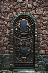 Vintage iron door in the wall of a house of wild stone