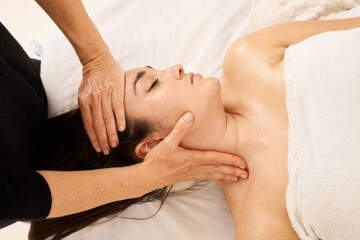 woman receiving a facial massage in the area of the cervicals