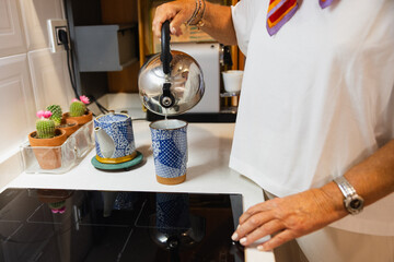 Detail photo of preparing an infusion with the teapot and the cup in the kitchen