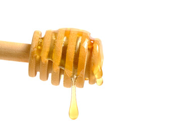 Liquid and fresh honey dripping from wooden honey spoon white background.