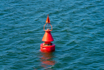 A red channel marker floating on ocean water