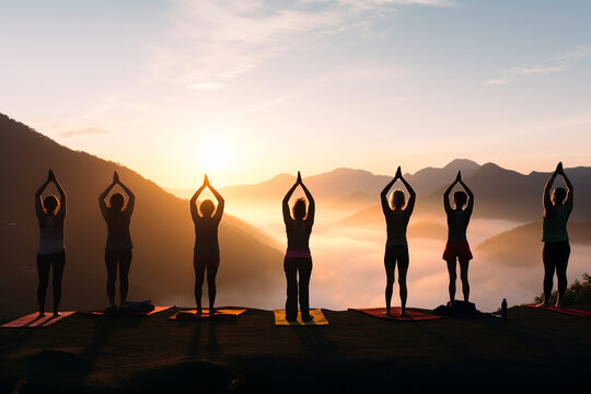 Healthy lifestyle, states of mind concept. Men and women doing yoga or meditation in mountains during sunny and warm summer sunset or sunrise. Dark human silhouettes in foggy mountains background