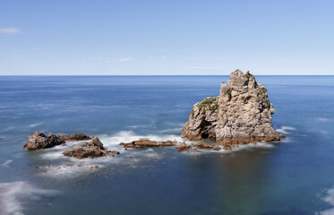 Fototapeta na wymiar Rocks in the blue waters of the cantabric sea, pendueles beach in Asturias, Spain.