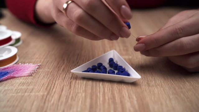 Beading concept. Woman making blue bead bracelet at home while sitting at table