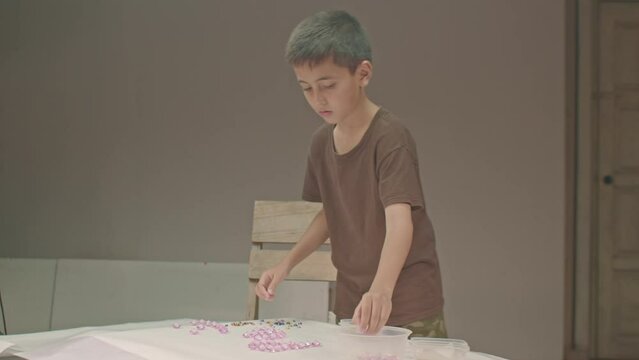 .The boy carefully uses the diamonds to make letters in the studio..high quality video 4K. studio shot..Playing with colorful gems is a great way for children to learn. ..colorful gems background