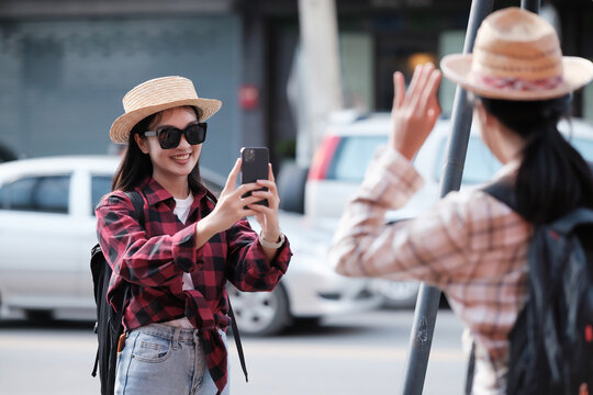 Asian female tourist takes a photo of a female friend while touring the city center.