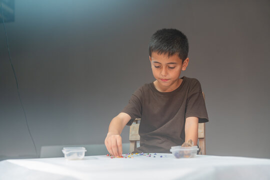 .The boy carefully uses the diamonds to make letters in the studio..high quality video 4K. studio shot..Playing with colorful gems is a great way for children to learn. ..colorful gems background