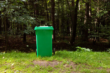 green plastic trash can in a forest park.