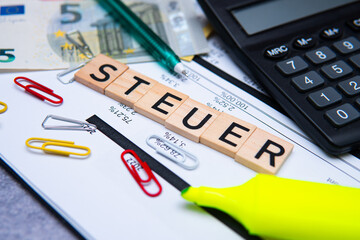 the inscription steuer, i.e. tax, next to banknotes and a calculator. Concept showing taxes in...
