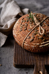 Baked sourdough bread from whole grain flour and pumpkin seeds on a grid, olive oil and black olive on a rustic wooden table. Artisan bread.
