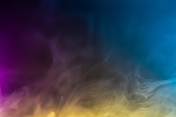 Blurred photo texture of colored smoke on a black background.