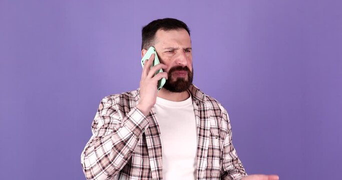 Annoyed young bearded man quarreling while talking on mobile phone. Angry man, stress.