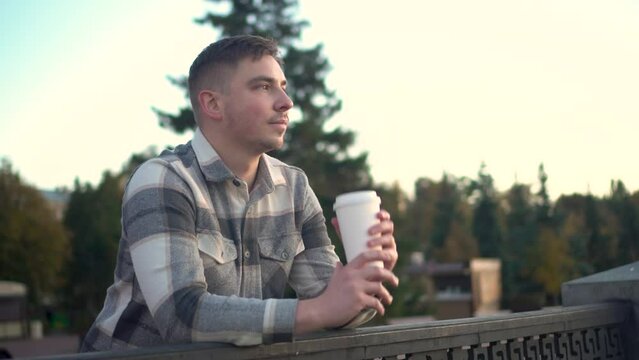 A young man with a glass of coffee in his hand.