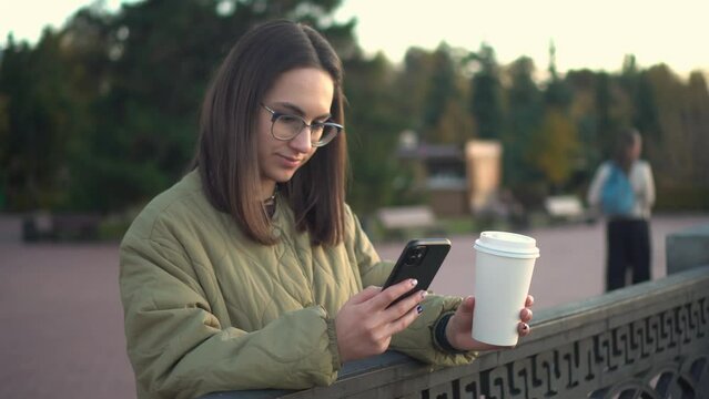 Woman is chatting on a smartphone with coffee