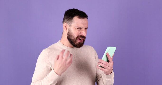 Annoyed young bearded man quarreling while talking on mobile phone. Angry man, stress.