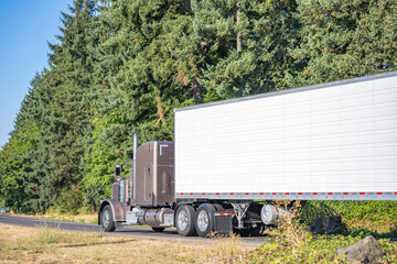 Classic light brown bonnet big rig semi truck transporting cargo in refrigerator semi trailer...