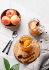 Homemade apple cider with apples and cinnamon in glasses on a light background with fresh fruits, spices and branch. The concept of an autumn or winter healthy drink.