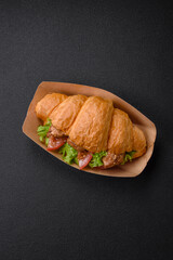 Delicious fresh crispy croissant with chicken or beef meat, lettuce, tomatoes, spices and sauce