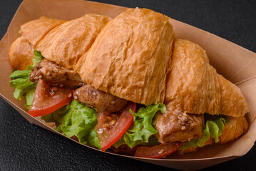 Delicious fresh crispy croissant with chicken or beef meat, lettuce, tomatoes, spices and sauce