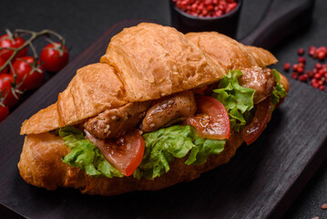 Delicious fresh crispy croissant with chicken or beef meat, lettuce, tomatoes, spices and sauce