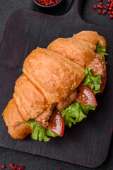 Delicious fresh crispy croissant with chicken or beef meat, lettuce, tomatoes, spices and sauce