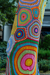 Colorful crochet knit on tree trunk in Kyiv, Ukraine. Street art goes by different names, graffiti...