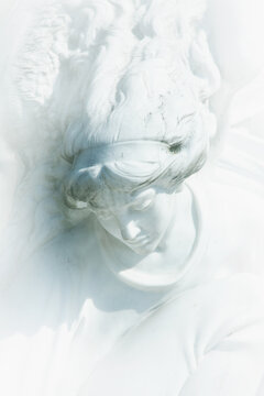 Vertical image of an ancient stone statue of white angel as symbol of love, faith and hope