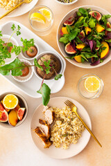 Delicious hearty lunch, brown rice with baked chicken breast and seeds, mixed salad with figs and peach, sprouted carrot and beet tops
