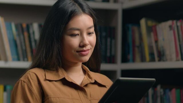 Asian woman girl student in university library reading ebook using digital tablet preparing exam checking task list timetable class learn new application for study concept education modern technology