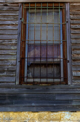 Fototapeta na wymiar Old wooden window with wrought iron bars on wood planked building