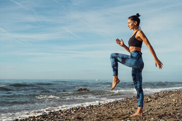 The girl is doing fitness on the seaside.