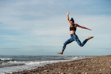 The girl is doing fitness on the seaside.